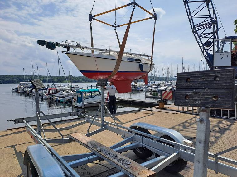 Segelyacht wird im Hafen mit dem Kran aus dem Wasser gehoben
